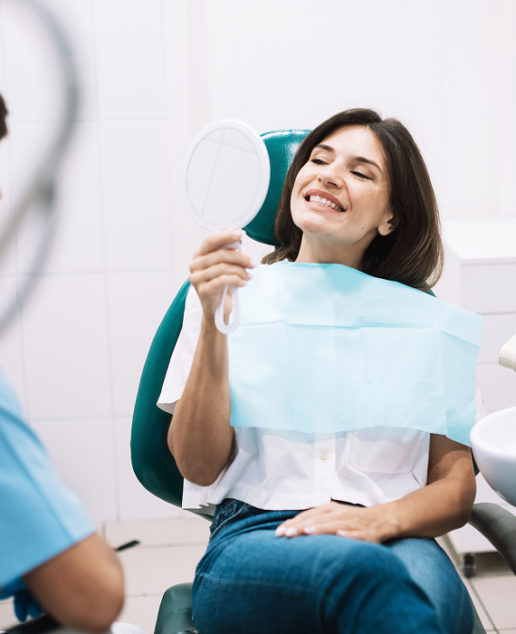 Smiling woman looking into mirror brushing her teeth smoothly